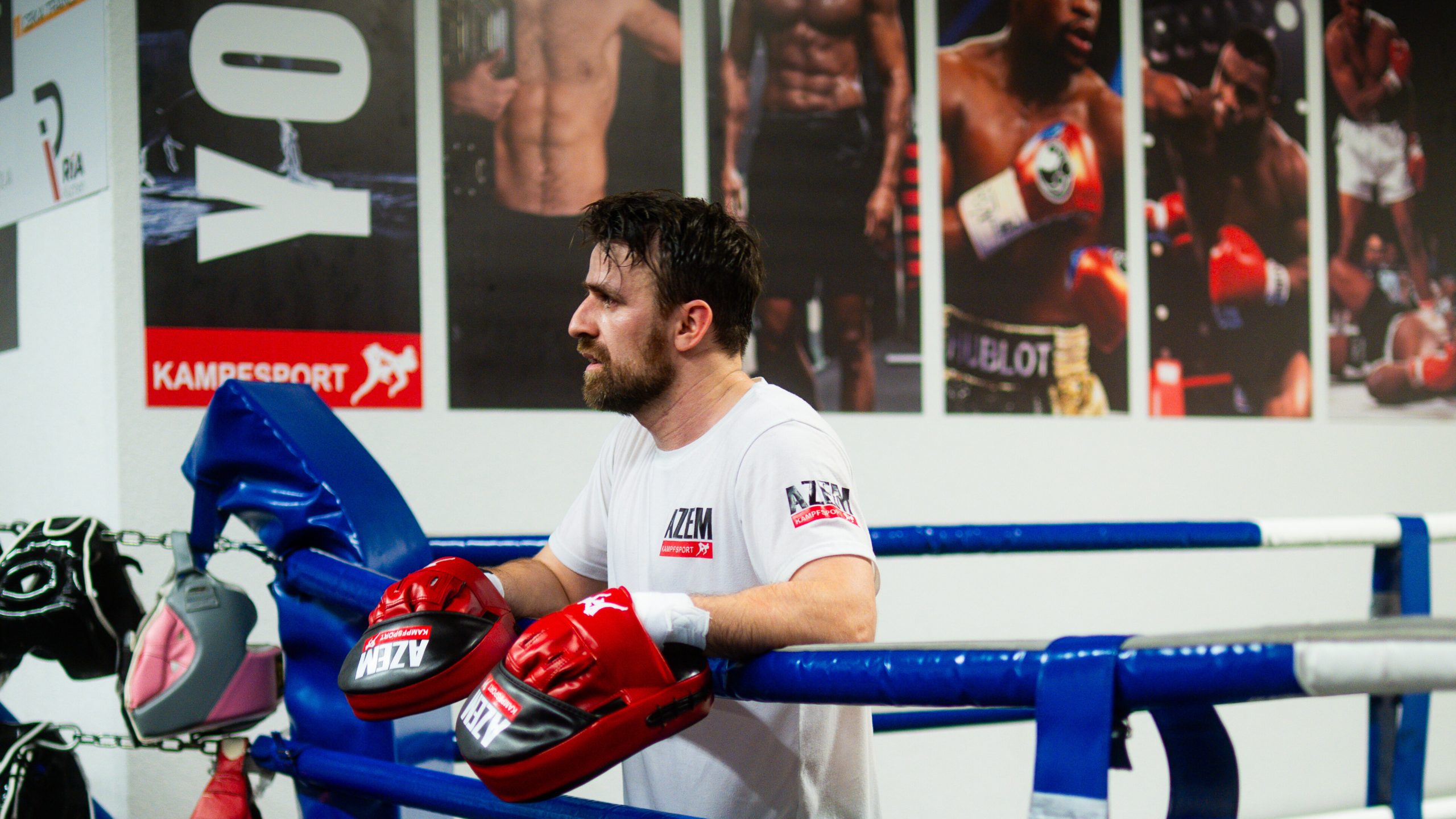 Boxtrainer lehnt mit Handschuhen an den Seilen des Rings bei AZEM Kampfsport