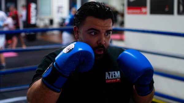 Boxer in Kampfstellung mit blauen Handschuhen im Ring.