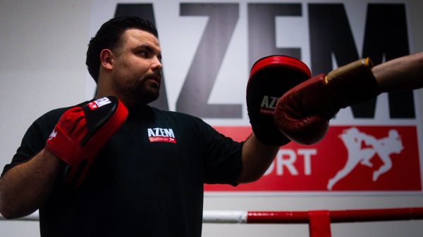 Trainer hält Pratzen für Schlagtraining im Ring.