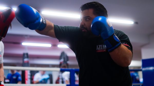 Boxer schlägt gezielt mit blauen Handschuhen gegen Pratzen.