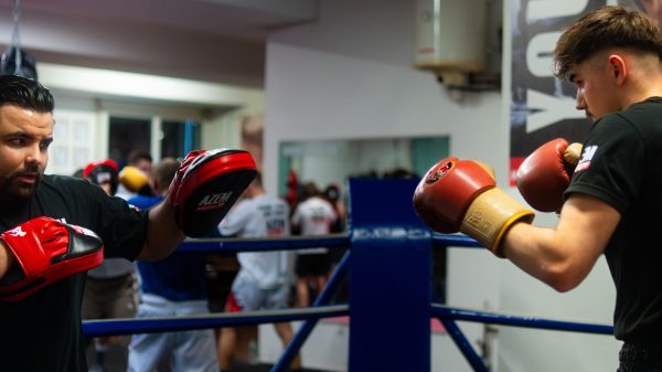 Trainer trainiert jungen Sportler mit roten Boxhandschuhen.