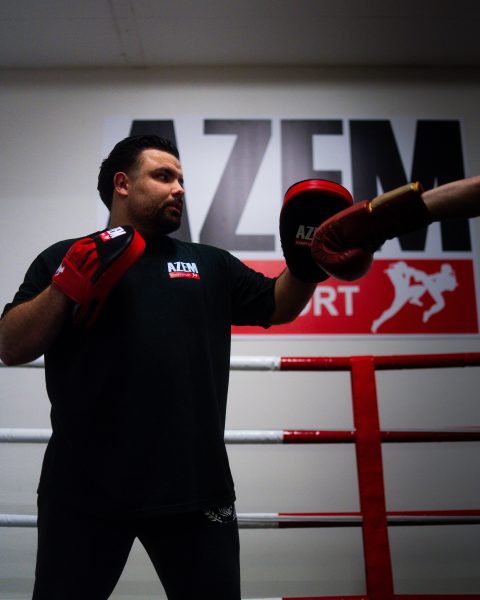 Trainer hält Pratzen für Schlagtraining im Ring.