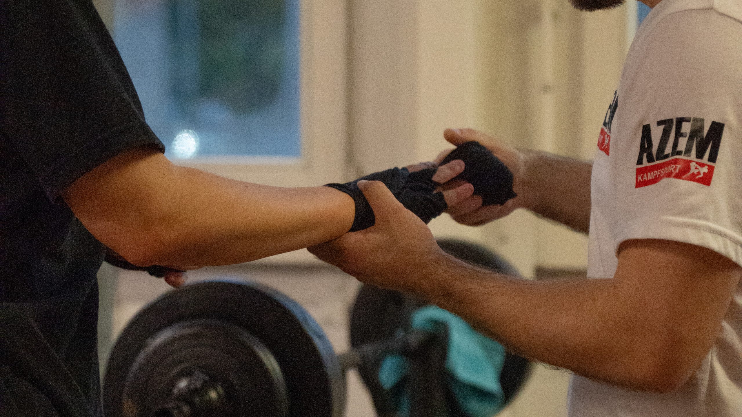 Trainer Meriton Ceka hilft beim Anlegen der Handbandage | Azem Kampfsport